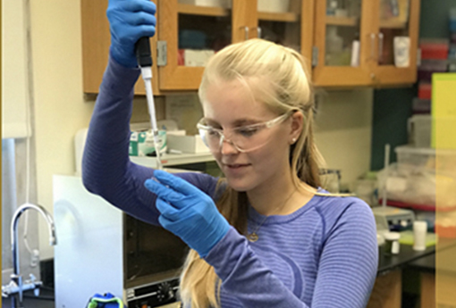 Girl student uses a pipette to extract DNA in a molecular bio lab at school