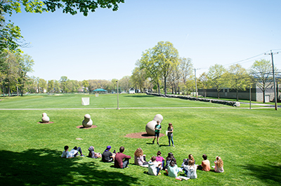 long shot of fields, fieldhouse, art sculpture and a class of students with teachers at The Wheeler Farm