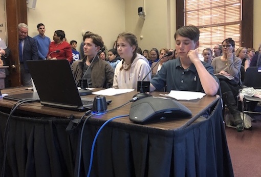 Three students of various ages sit at a governmental hearing to testify about being dyslexic.