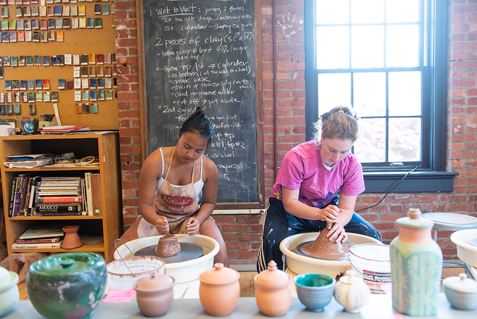 Girls work at throwing wheels in the ceramics art studio.