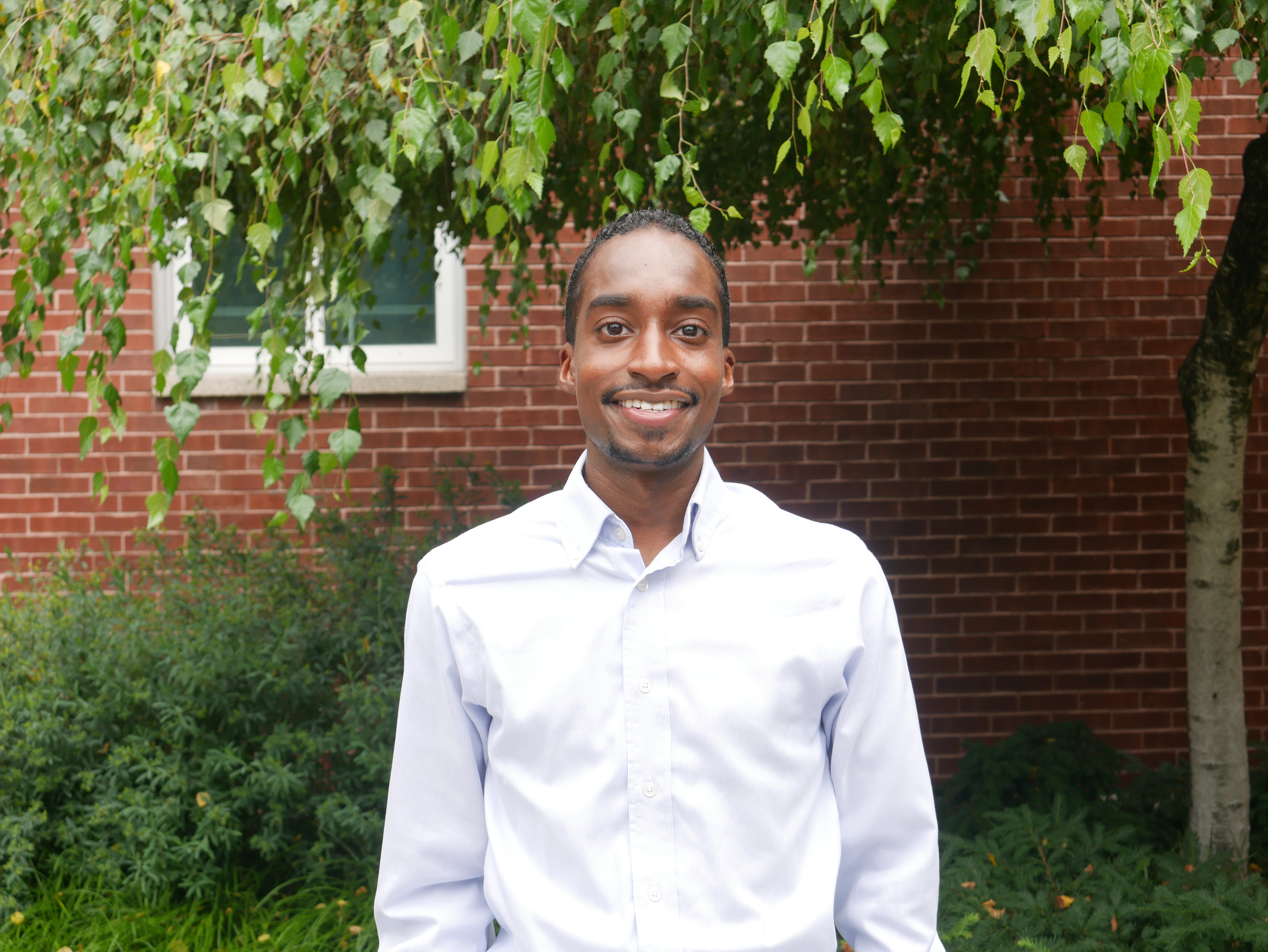 Man smiling outside on campus.