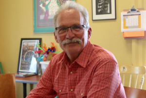 Man in glasses sitting in a school office.