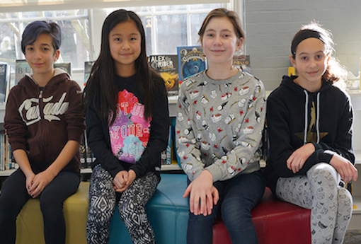 Four middle school girls who have written novels in a special elective class pose in the Learning Commons.