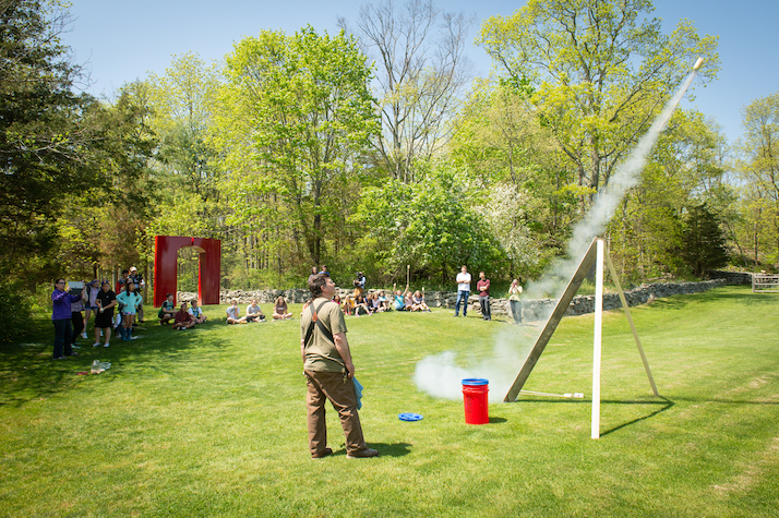 Teacher launches rockets in front of a class outdoors at the Wheeler Farm.