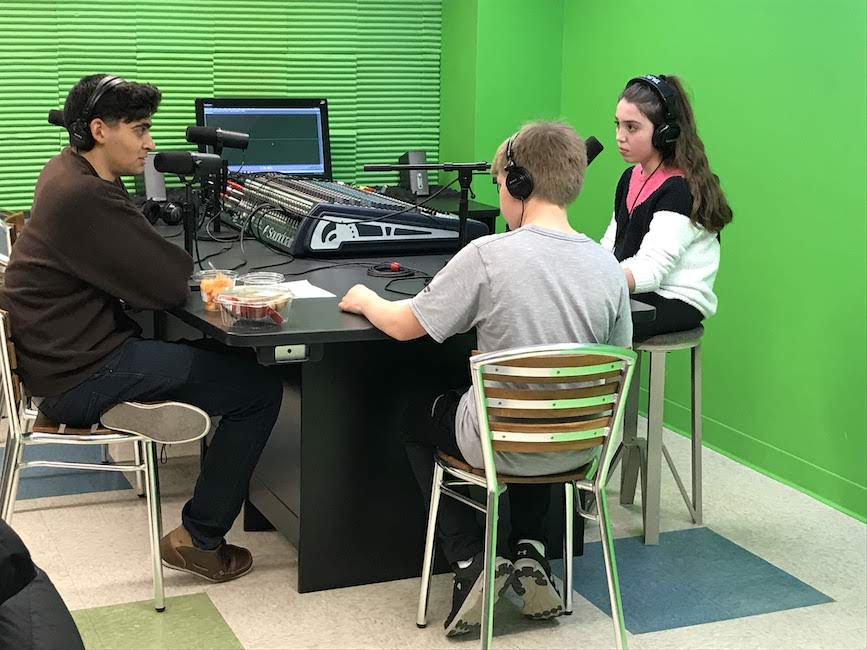 Two young students interview global entrepreneur Cliff Weitzman for a podcast in the Digital Production Studio.