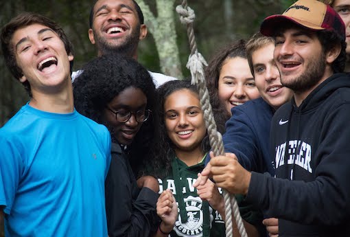 Class of 2019 students squeeze onto a low element at the ropes course at the Farm.