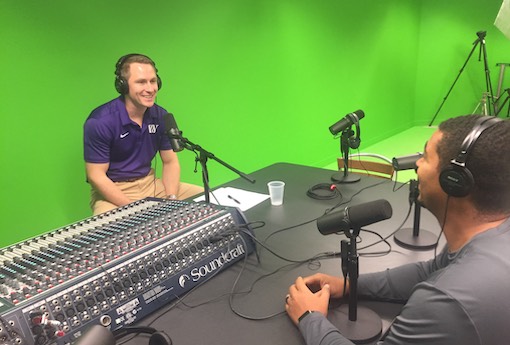 Two coaches sit in a radio studio recording a podcast about athletics.