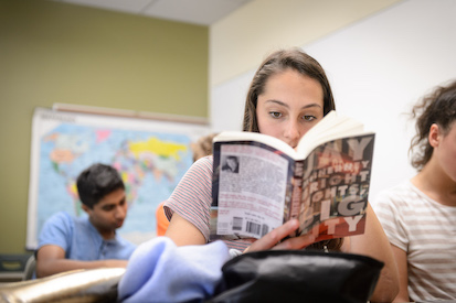 Girl reading a paperback book in class.