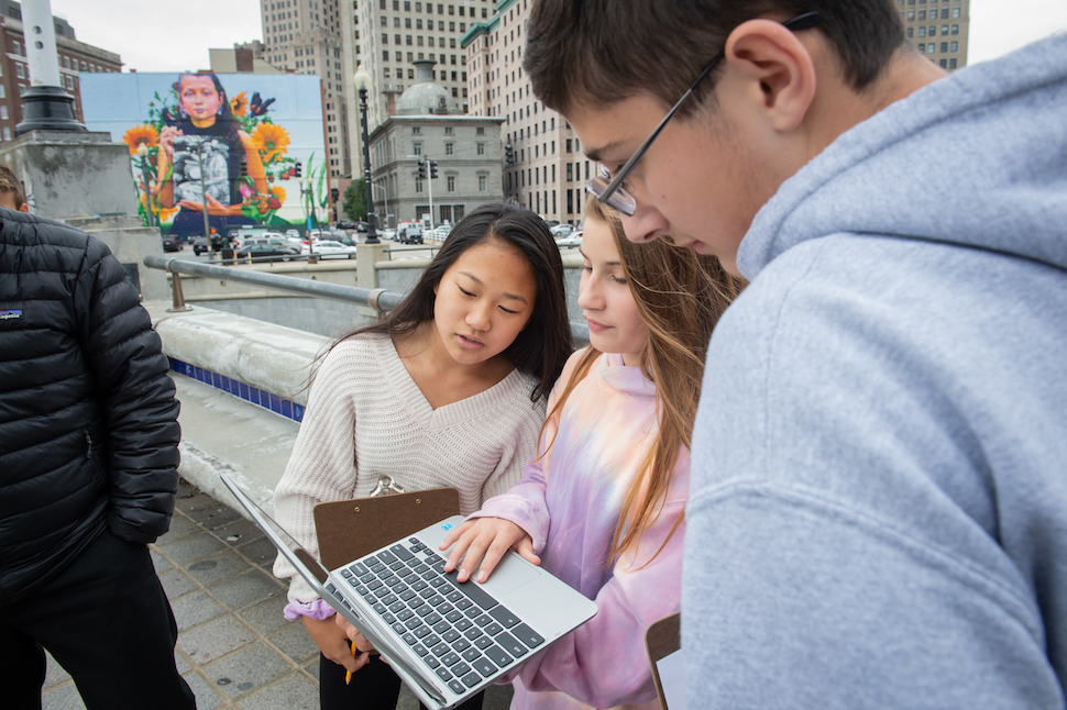 Students in the city look at a laptop.