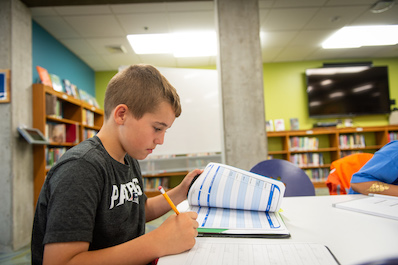 Boy works on homework in library.