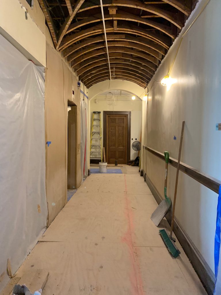 Closed wooden door at the end of a hallway under construction.