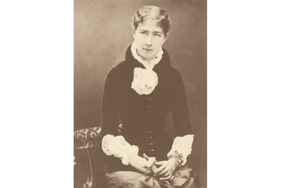 School founder Mary Wheeler in Victorian dress sitting with hands folded.