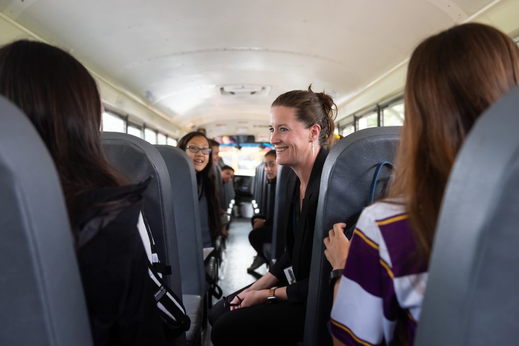 Middle School Director Vanessa O'Driscoll and 8th graders share a laugh on a bus.