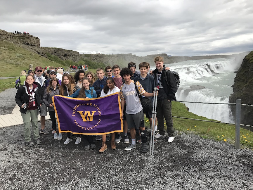 Students and teachers pose with School flag in Iceland.
