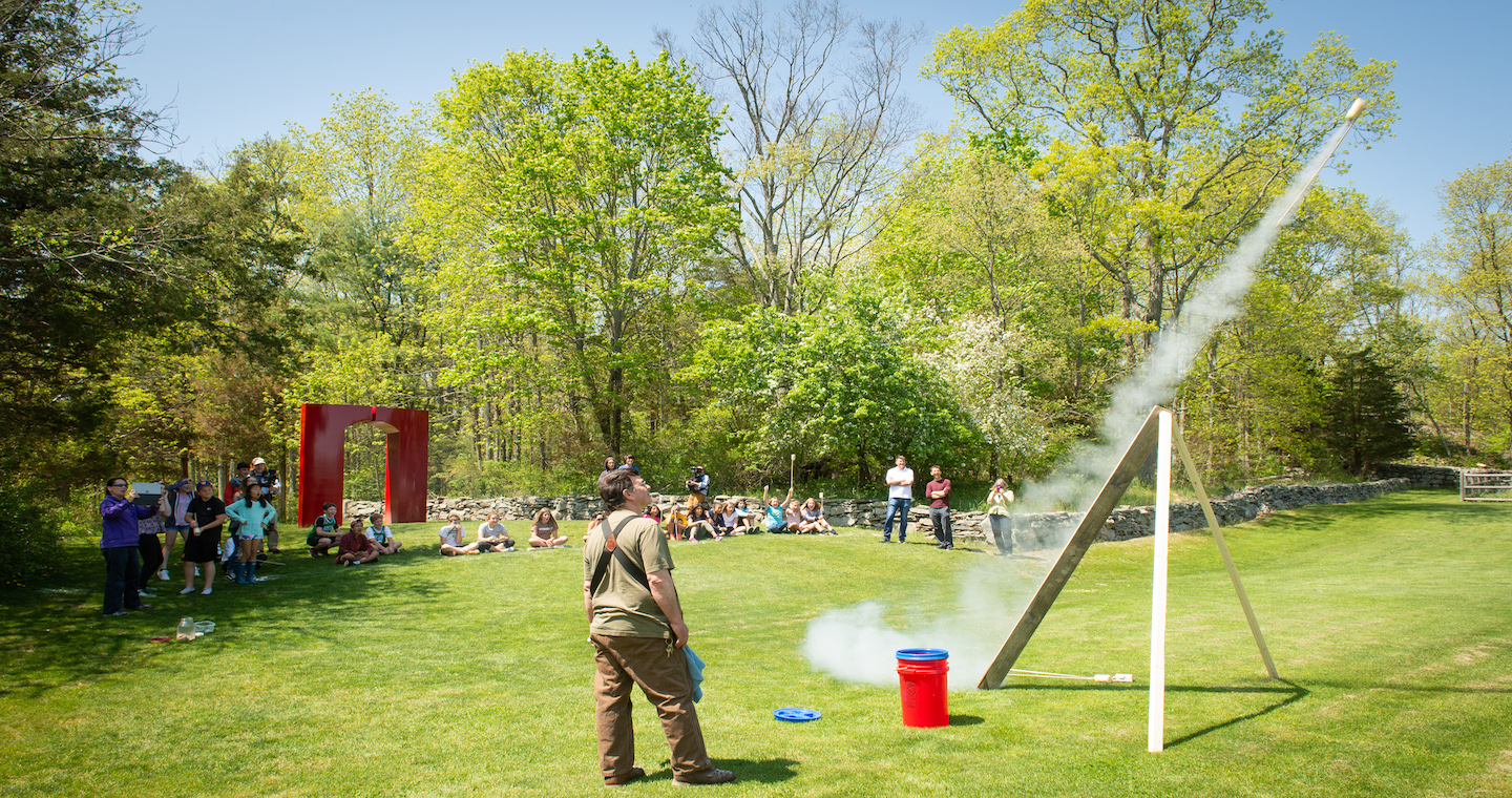 Students watch as teacher fires sugar rocket into the air at the Wheeler Farm campus.
