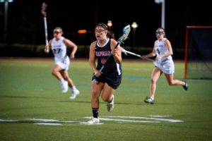 Girl playing lacrosse on a field 