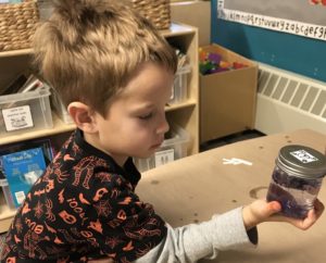 Young student holds a glitter jar in class.