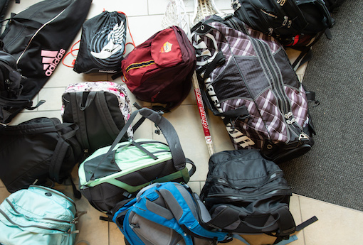Group of backpacks lying on the ground inside a building.