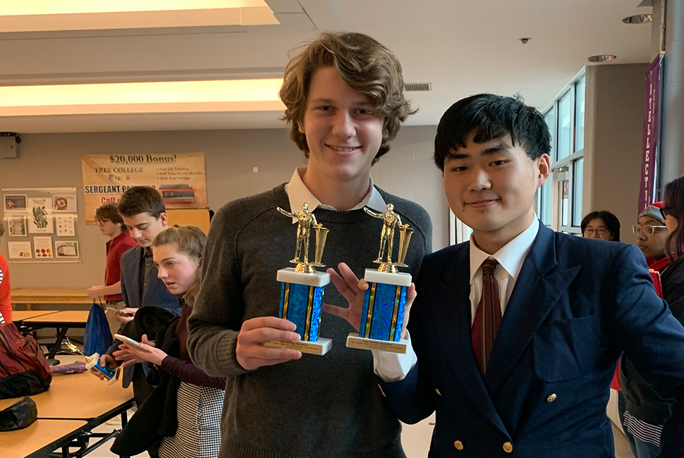 Debate teammates hold trophies.