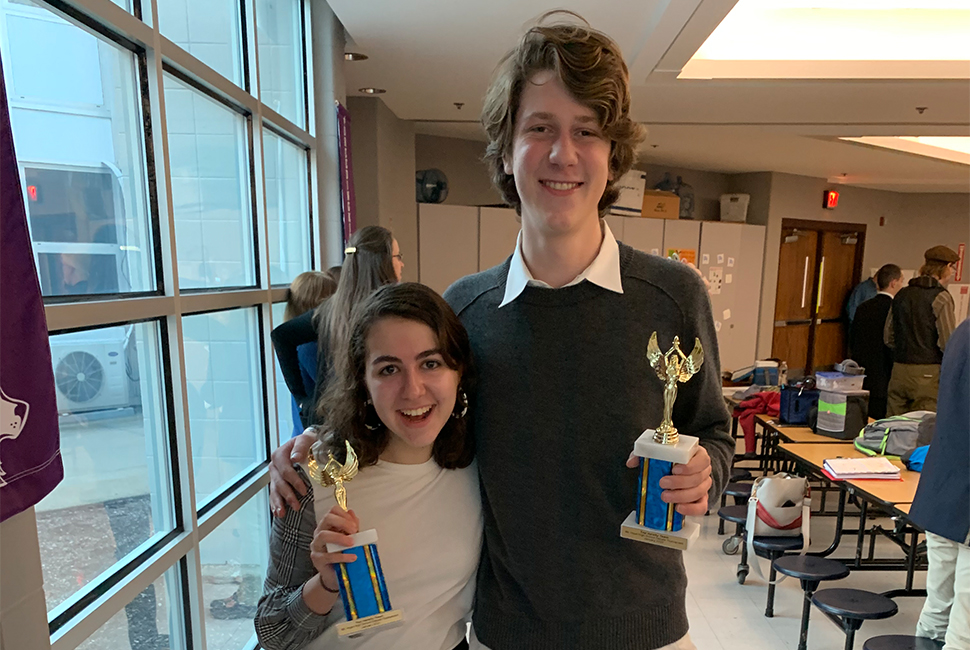 Debate team members hold trophies.