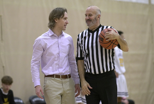 Coach and referee talk at basketball game.