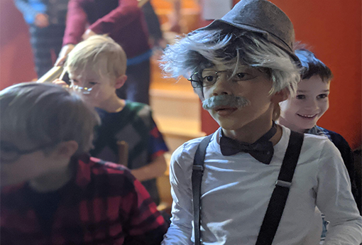 Young boy dressed as 100 year old man with hat, grey hair and mustache.