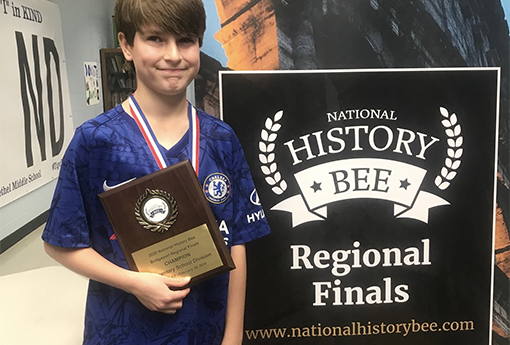 Boy holding award plaque for History Bee regional competition.
