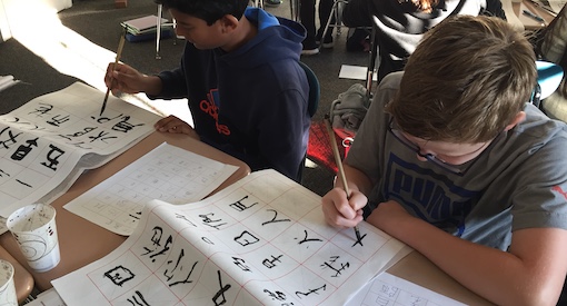 Students work creating Chinese letters on scrolls