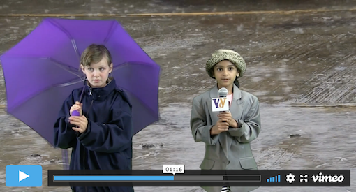 Two young girls present a weather forecast in front of a green screen of rain.