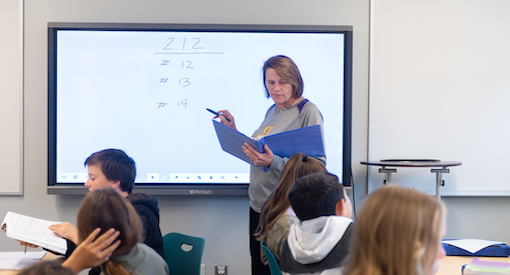 Teacher stands at screen in Middle School Math Class
