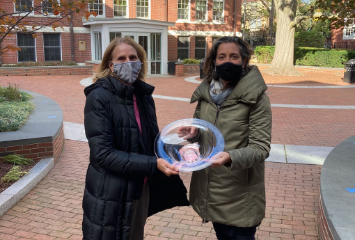 Two women holding a glass bowl outside