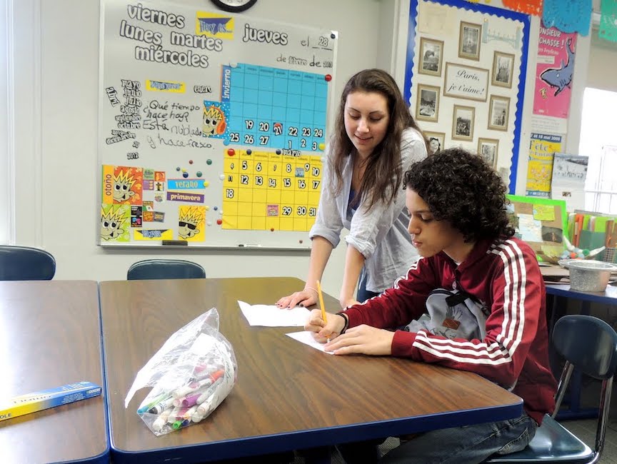 College-age teacher works with student in language classroom.