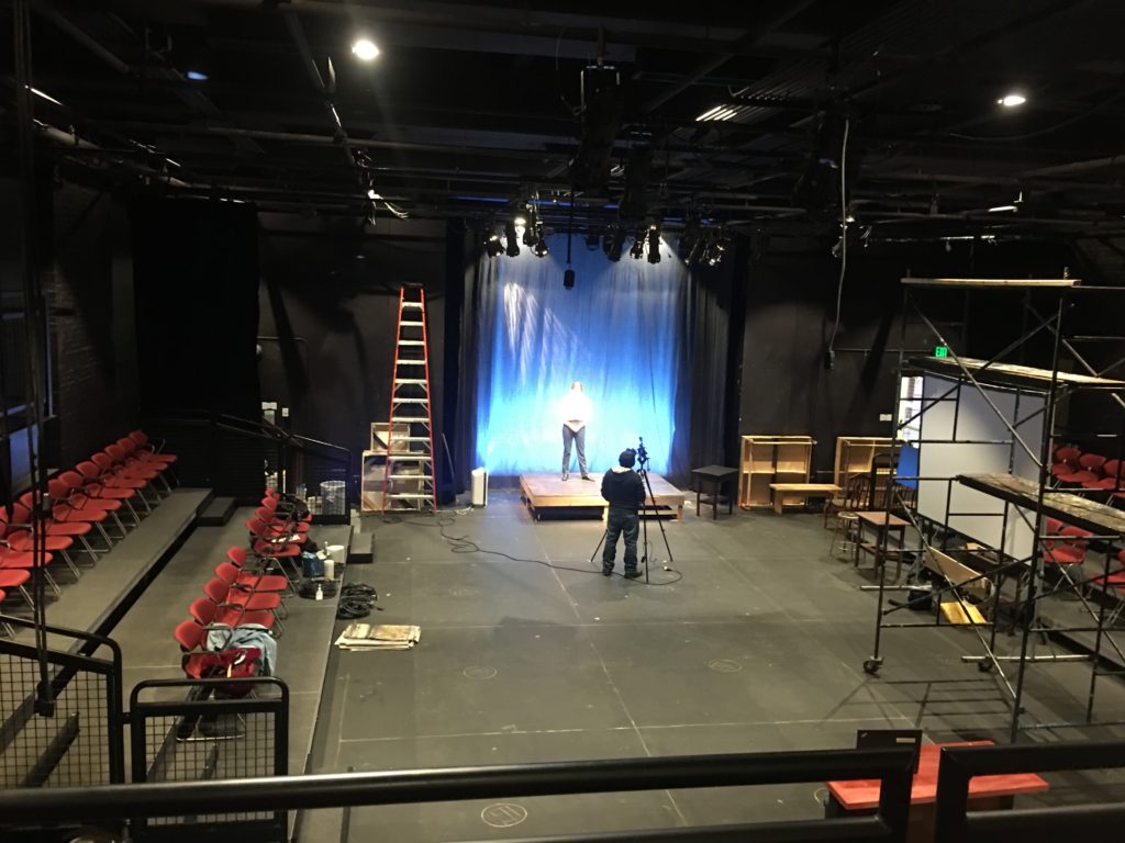 An actor and videographer work on a stage to record part of a pandemic production of the high school fall play.