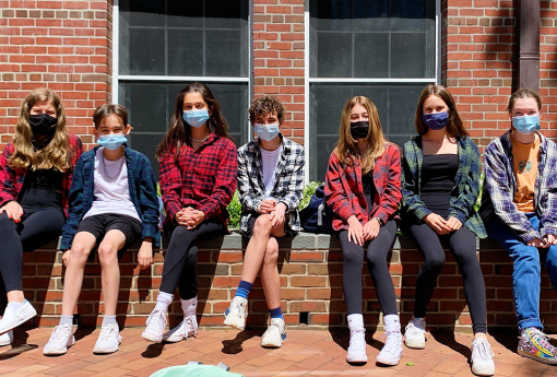 Group of Middle School students sit on a wall