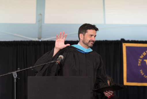 man waving from podium