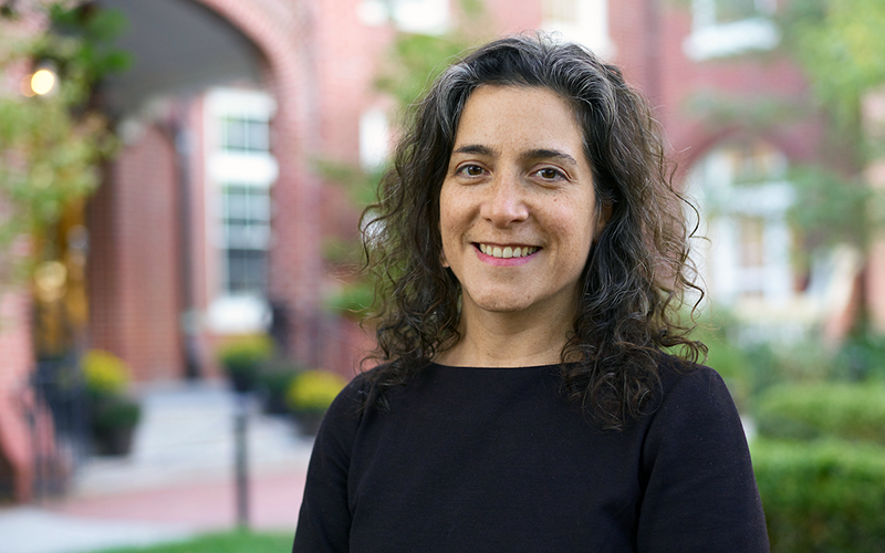 Head of School Allison Gaines Pell standing in front of the Wheeler main building in Providence and smiling at the camera.