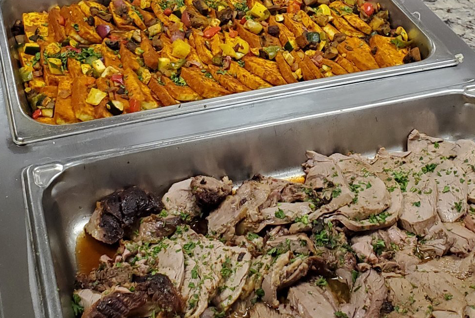 Pork and squash dishes in metal containers.