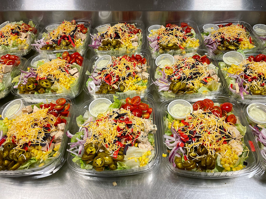 Salads lined up in plastic containers.