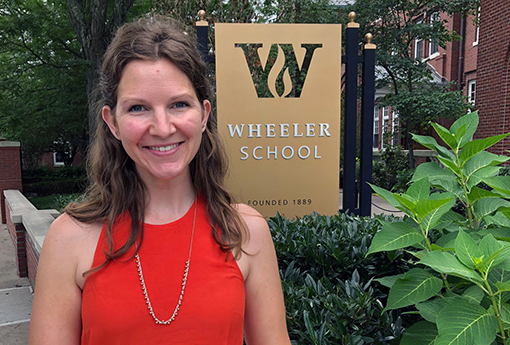 nrollment Director Anna Curtis standing in front of the Wheeler School sign outside the front of the building and smiling at the camera.