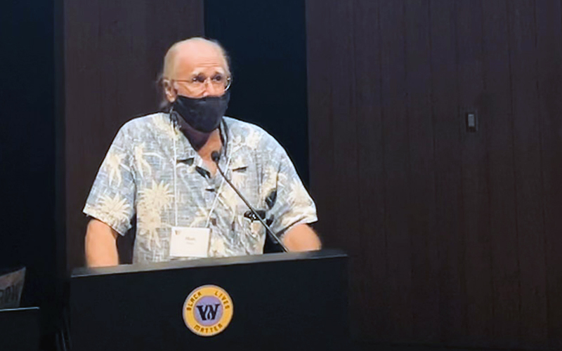 Mark Harris, standing at a podium and wearing a medical/COVID mask) addressing the all-school faculty and staff meetin.