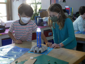 Third-grade students building a lighthouse in Wheeler's DIB Lab. The light at the top of the model lighthouse is on and two students are looking at it.