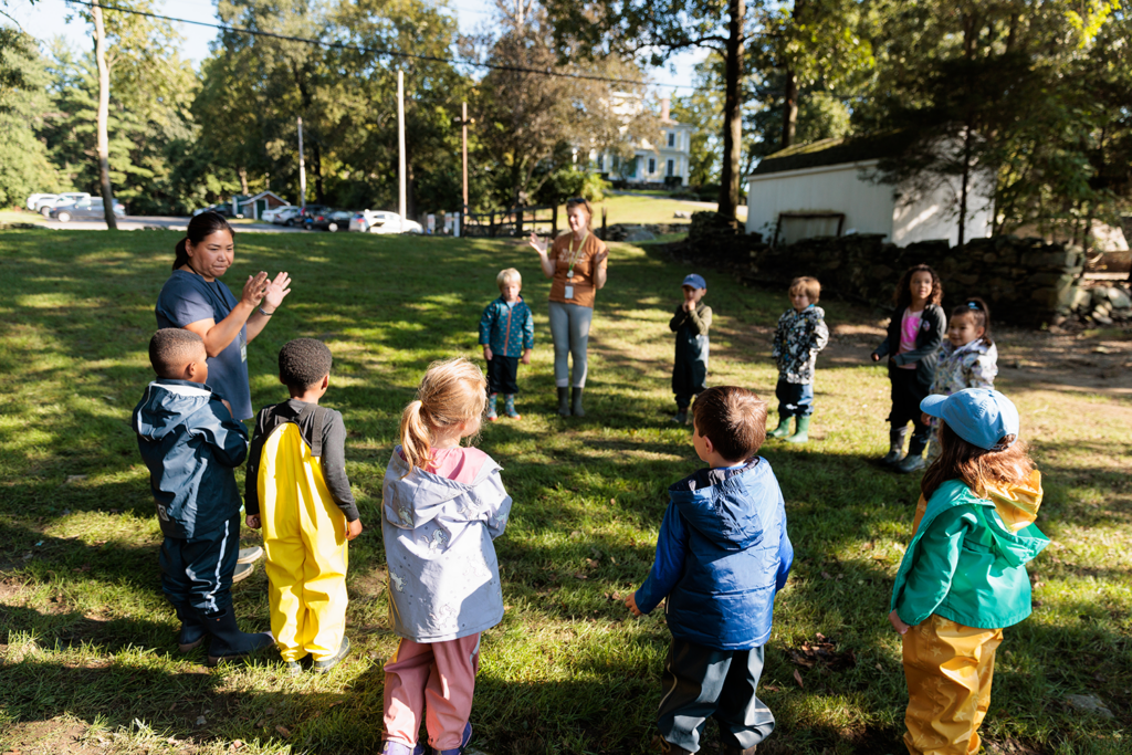 Kindergarteners and their teachers gathering in a circle at Wheeler Farm.