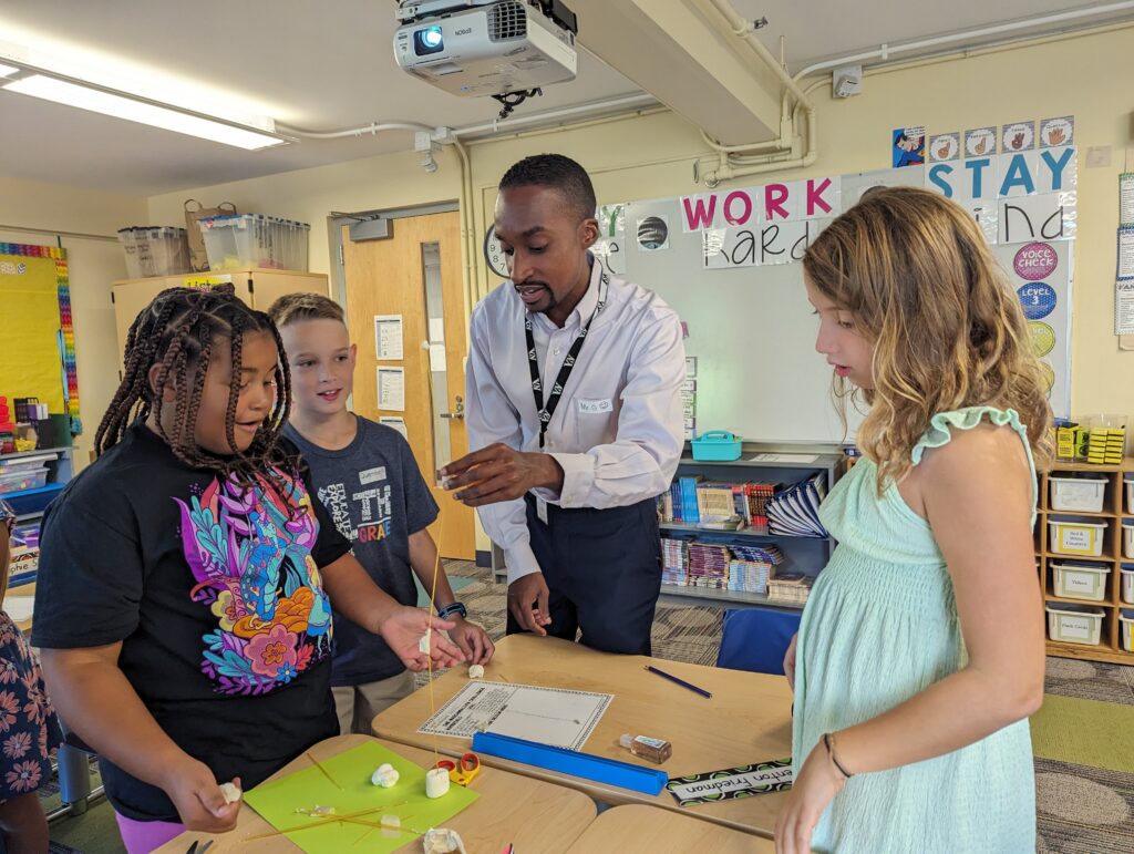 Students are participating in a community building lesson involving cooperation and marshmallows.