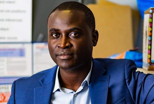 Photo of Omar Bah. He is looking at the camera, is wearing a blue sport coat and light blue shirt, and appears from the chest up.
