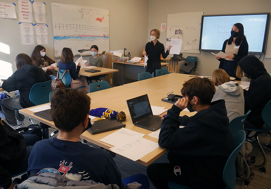 Poet Kate Colby stands at the front of a class with poetry in hand as she hosts a writing workshop for 7th-grade students.