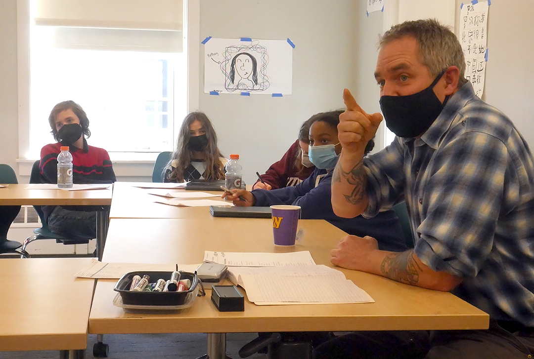 Journalist and former war correspondent C.J. Chivers points to a white board while 7th-graders listen to his instructions during a writing workshop.