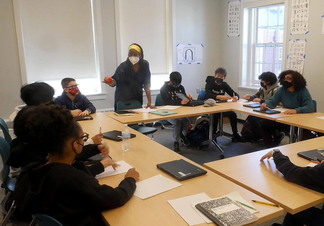 Children’s book author and poet Mariahadessa Ekere Tallie holds an apple in front of 7th-graders gathered around her while leading a writing workshop