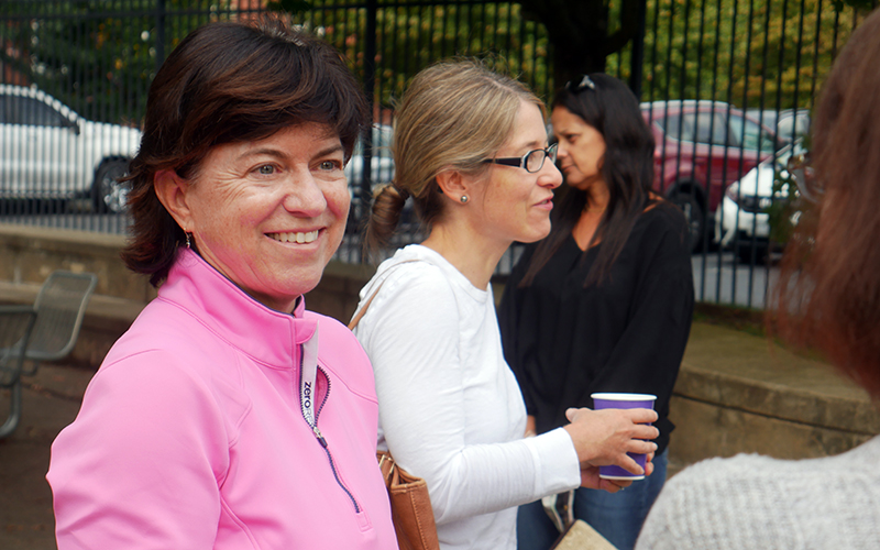 Chris Rogers smiles at another person during a WSPA coffee event held outside. A few other parents talk in the background.