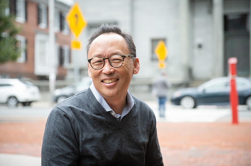 Young Un stands outside in downtown Providence and smiles at the camera.