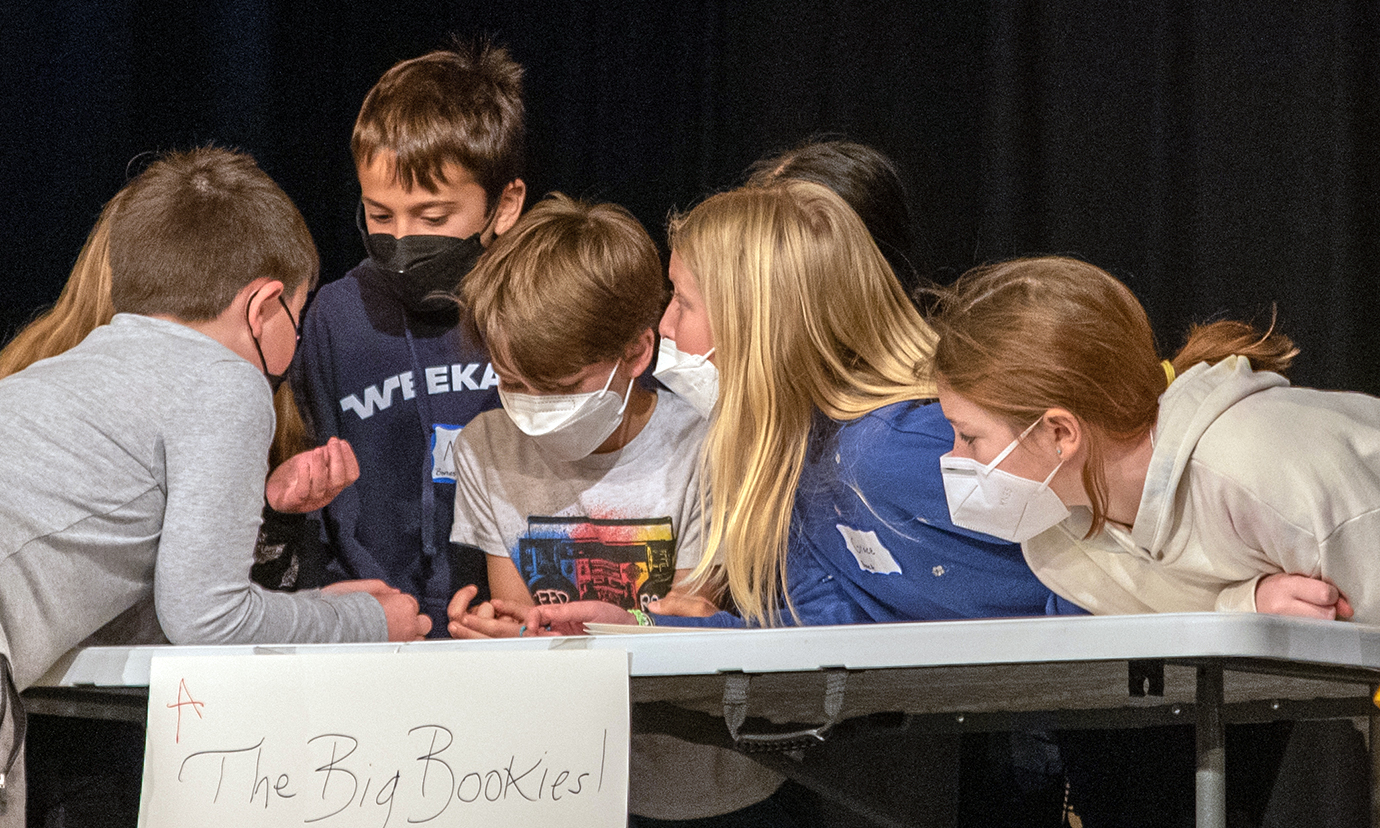 Students lean together and talk while answering trivia questions at the Battle of the Books.